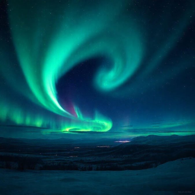 Vibrant auroras paint the night sky over a mountainous landscape, capturing the breathtaking natural phenomenon.