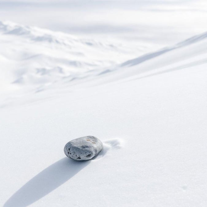 A simple yet striking image of a gray stone in a snowy landscape, perfect for creating a peaceful atmosphere on your device.