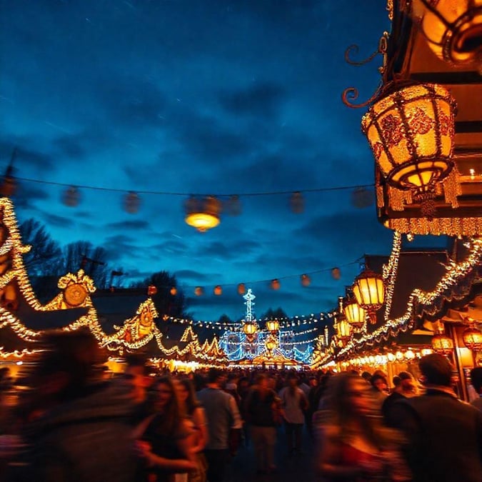 A lively scene at an Oktoberfest celebration, filled with people enjoying the festive atmosphere. The image captures a bustling street adorned with fairy lights and lanterns, creating a magical ambiance typical of this traditional event.