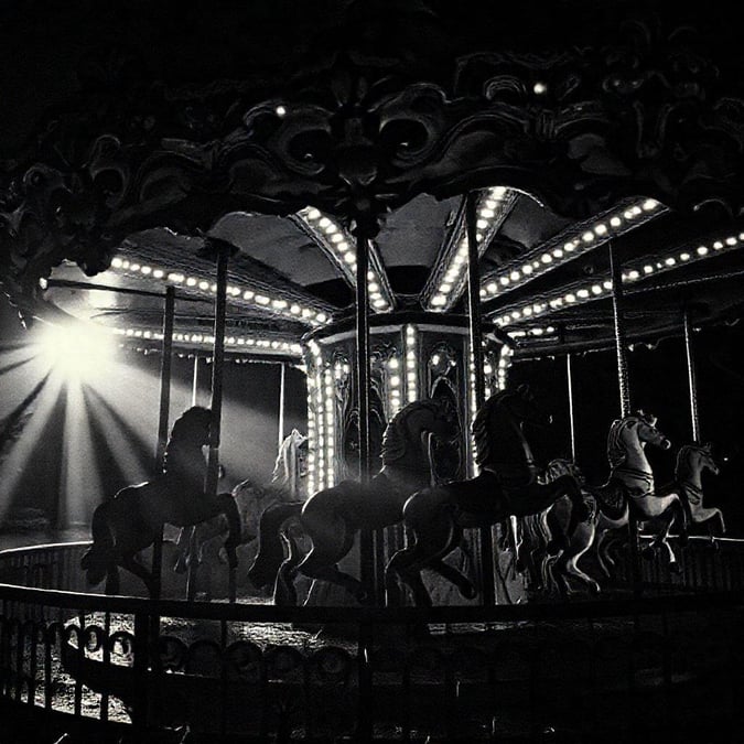 A classic carousel ride at night with illuminated lights shining through the gloom.