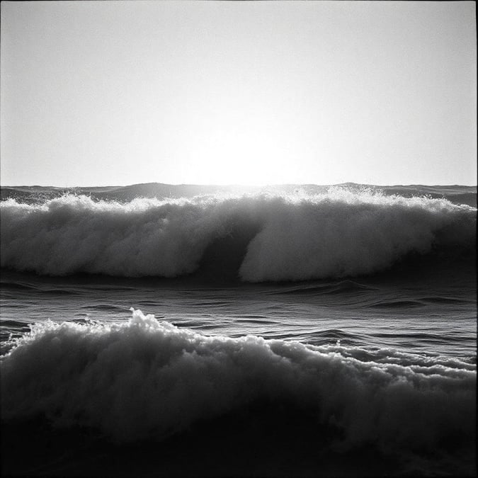 A dramatic black and white view of the ocean, showcasing the power and beauty of nature. A photograph capturing a moment at sunset when waves are breaking with great force.