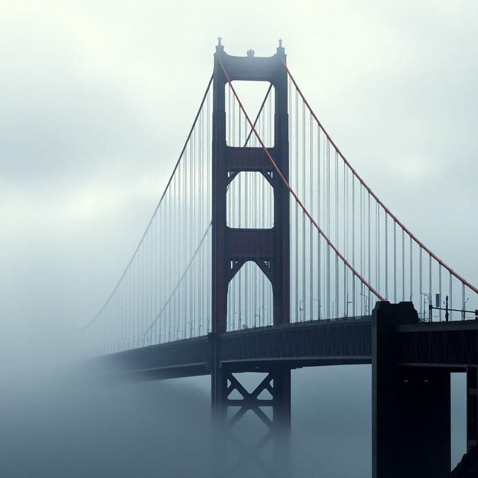 A majestic view of the Golden Gate Bridge on a foggy day, with its iconic design standing out against the misty backdrop. Perfect wallpaper for urban enthusiasts.