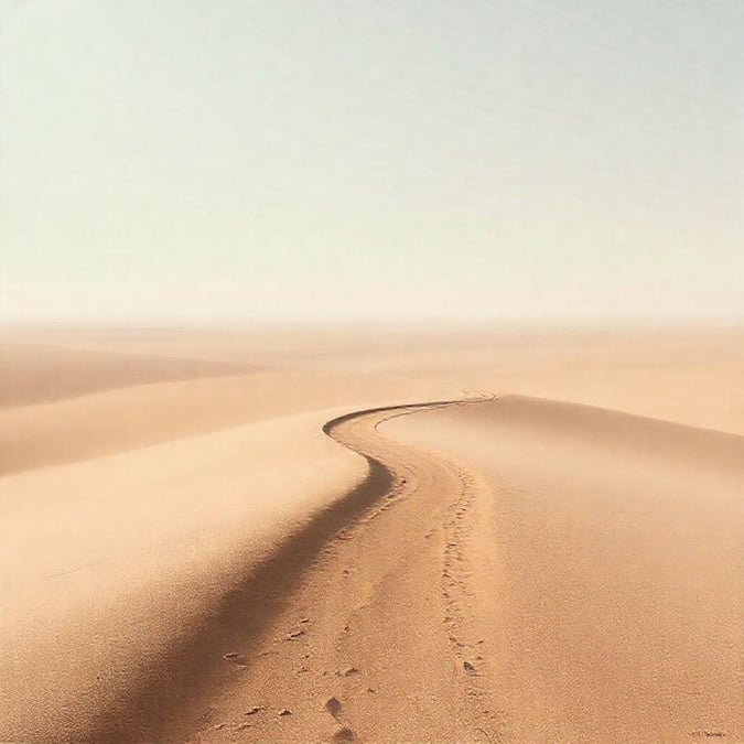 A tranquil view of a winding trail in the sandy expanse of a desert, with a minimalist feel that evokes solitude and adventure.