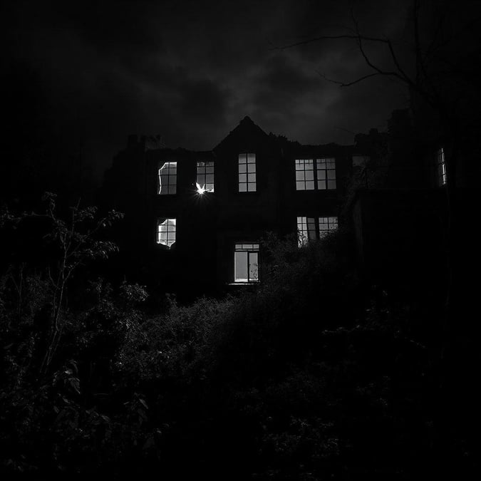 The ominous night of Halloween at an abandoned building, with every window a glowing eye in the darkness.