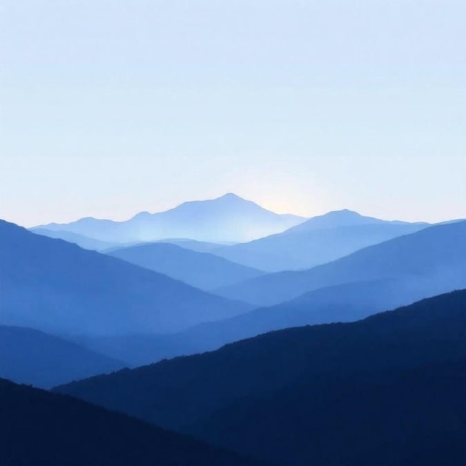 A tranquil scene of tall, towering mountains with fog rolling in at sunset. A serene minimalist wallpaper for your desktop or mobile.