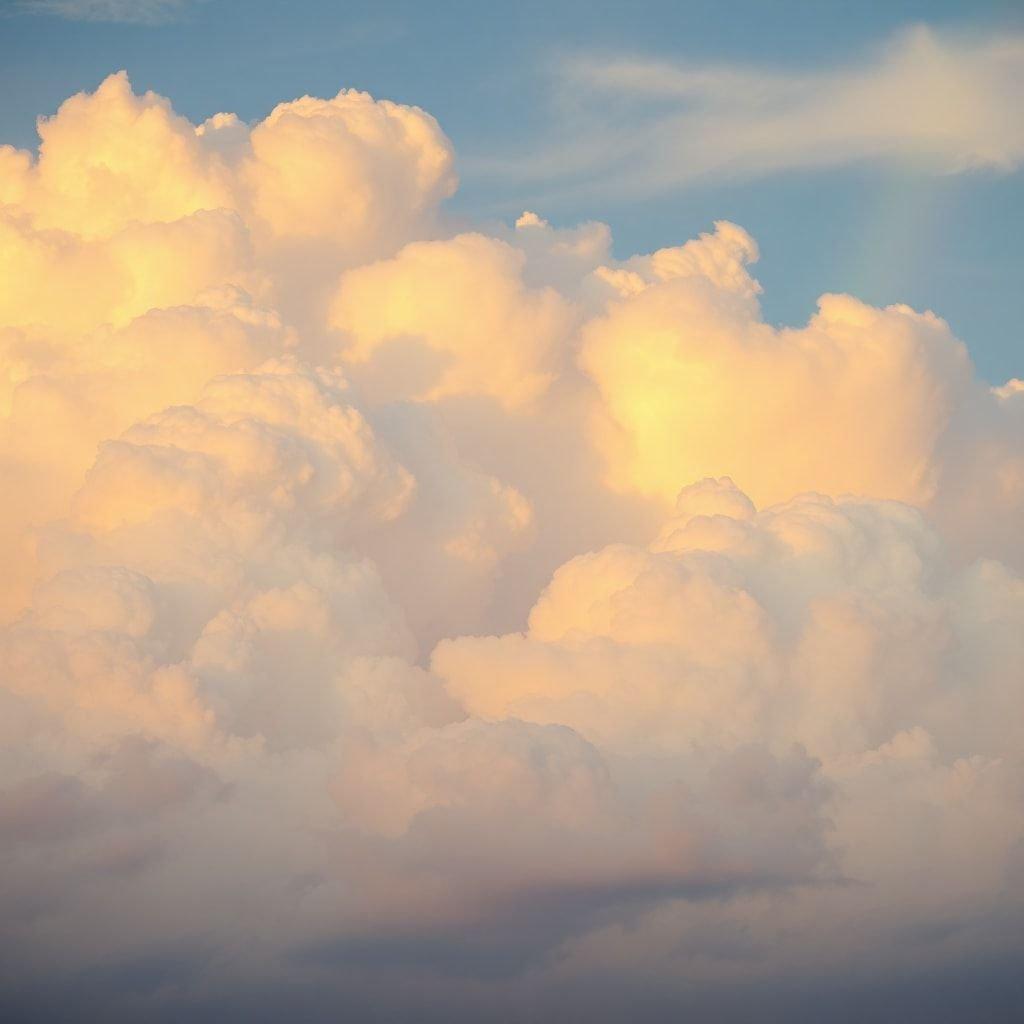 A picturesque cloudy sky with radiant hues of orange and pink, creating a serene backdrop. Capture the beauty of nature with this vibrant wallpaper.